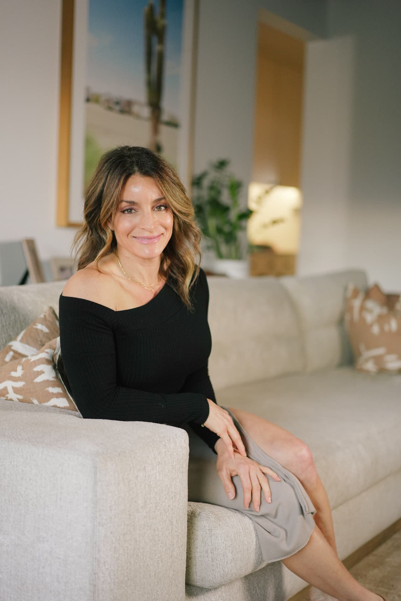 Kacey Taormina seated on a linen sofa in a sunlit California living room
